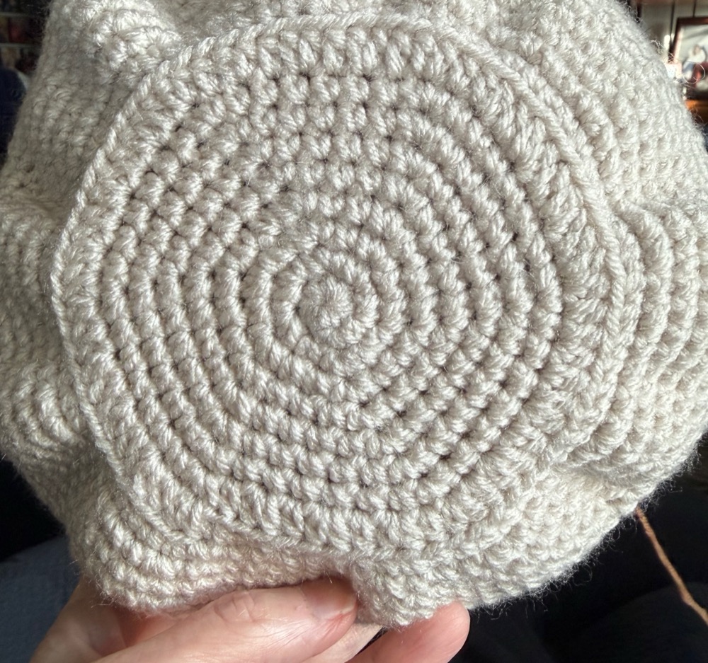 The flat base of a crocheted amigurumi body worked in cream yarn, clearly six-sided with a corner at each of six points